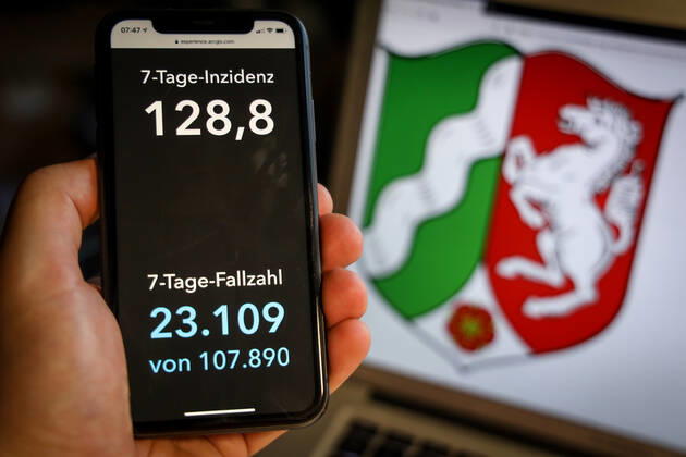 Coronavirus in Deutschland - Covid-19-Dashboard des Robert Koch-Institut DEU, Deutschland, Nordrhein-Westfalen, 28.03.2021: Die 7-Tage-Inzidenz für das Bundesland (Fälle letzte 7 Tage 100.000 EW) wird auf einem iPhone angezeigt, im Hintergrund das Landeswappen