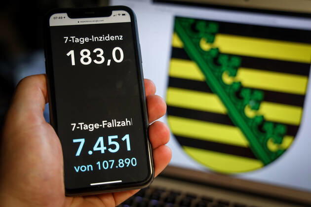 Coronavirus in Deutschland - Covid-19-Dashboard des Robert Koch-Institut DEU, Deutschland, Sachsen, 28.03.2021: Die 7-Tage-Inzidenz für das Bundesland (Fälle letzte 7 Tage 100.000 EW) wird auf einem iPhone angezeigt, im Hintergrund das Landeswappen