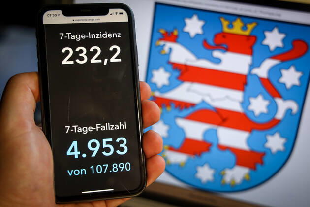 Coronavirus in Deutschland - Covid-19-Dashboard des Robert Koch-Institut DEU, Deutschland, Thüringen, 28.03.2021: Die 7-Tage-Inzidenz für das Bundesland (Fälle letzte 7 Tage 100.000 EW) wird auf einem iPhone angezeigt, im Hintergrund das Landeswappen