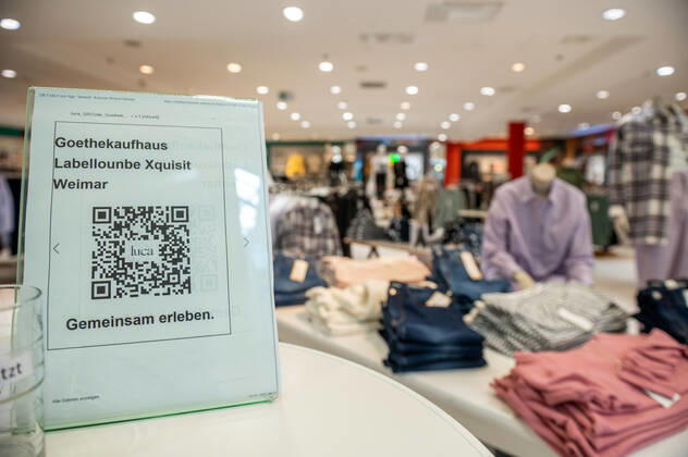 29.03.2021 Weimar: Ein Aufsteller mit einem QR-Code der Luca App steht in einem Geschäft für Kleidung der Konsumgenossenschaft Weimar. Weimar öffnet als erste Stadt in Thüringen vom 29. bis 31. März testweise alle Geschäfte der Innenstadt für Einkäufe - Bedingung ist ein aktueller negativer Corona Schnelltest.