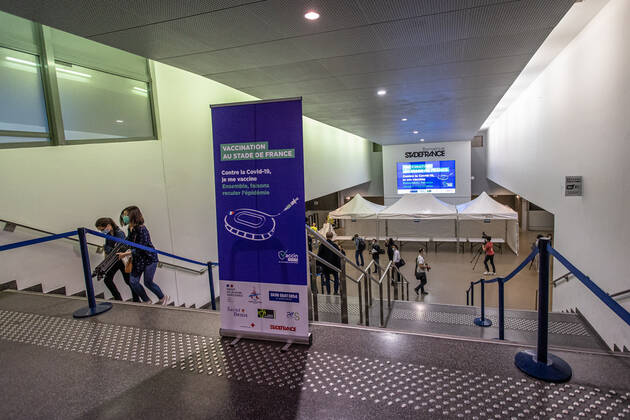 Coronavirus in Frankreich, neues Impfzentrum im Stade de France in Paris (210331) -- SAINT-DENIS (FRANCE), March 31, 2021 -- People walk past a sign of a new COVID-19 vaccination center in Saint-Denis, France, on March 31, 2021. Starting from mid-April people over 60 in France will be able to get vaccinated, from May 15 the vaccination will be open to people aged between 50 and 60 and from mid-June the age limit will be lifted, said French President Emmanuel Macron on Wednesday. (Photo by Xinhua) FRANCE-SAINT-DENIS-VACCINATION CENTER AurelienxMorissard 