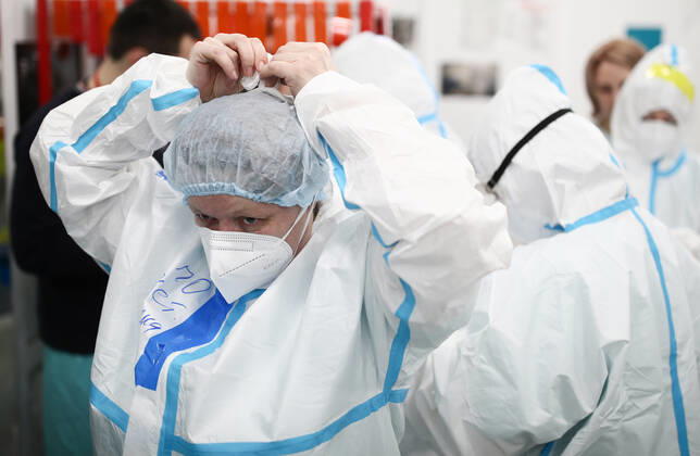 MOSCOW, RUSSIA - APRIL 1, 2021: Medical workers put on protective gear ahead of a shift at a temporary COVID-19 hospital at the Sokolniki Exhibition and Convention Center. The treatment facility has a reserve hospital and an observation center; its capacity is 550 beds, including 18 for intensive therapy patients. Sergei Bobylev TASS  TS0FB34C