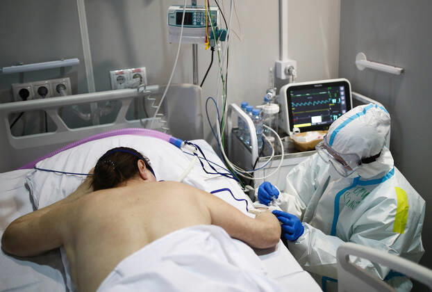 MOSCOW, RUSSIA - APRIL 1, 2021: A medical worker treats a patient at a unit of a temporary COVID-19 hospital at the Sokolniki Exhibition and Convention Center. The treatment facility has a reserve hospital and an observation center; its capacity is 550 beds, including 18 for intensive therapy patients. Sergei Bobylev TASS  TS0FB35B