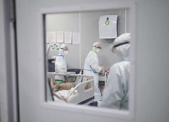 MOSCOW, RUSSIA - APRIL 1, 2021: Medical workers treat a patient at a unit of a temporary COVID-19 hospital at the Sokolniki Exhibition and Convention Center. The treatment facility has a reserve hospital and an observation center; its capacity is 550 beds, including 18 for intensive therapy patients. Sergei Bobylev TASS  TS0FB3C1