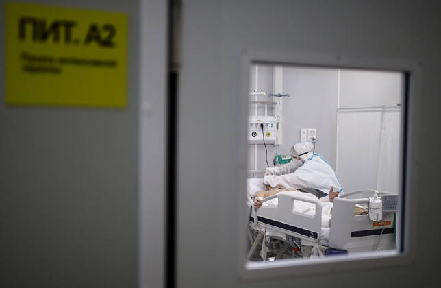 MOSCOW, RUSSIA - APRIL 1, 2021: A medical worker treats a patient at a unit of a temporary COVID-19 hospital at the Sokolniki Exhibition and Convention Center. The treatment facility has a reserve hospital and an observation center; its capacity is 550 beds, including 18 for intensive therapy patients. Sergei Bobylev TASS  TS0FB3C2