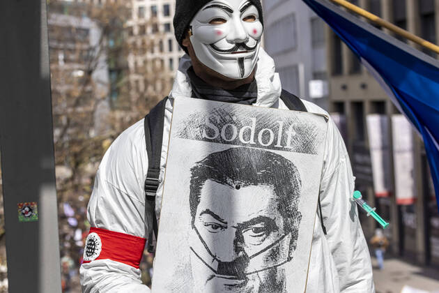 Ein Querdenker versteckt sich hinter einer Anonymous Maske und präsentiert Bayerns Ministerpräsident Söder als Södolf und damit als Hitler-Imitat. Querdenker und andere Gegner der Pandemie-Einschränkungen haben in Stuttgart ohne Abstand und meist ohne Schutzmaske demonstriert. Mindestens vier Demos mit 2500 Teilnehmern waren angemeldet, gekommen waren aber weit mehr. 03.04.2021: Europa, DEU, Deutschland, Baden-Württemberg, Stuttgart.