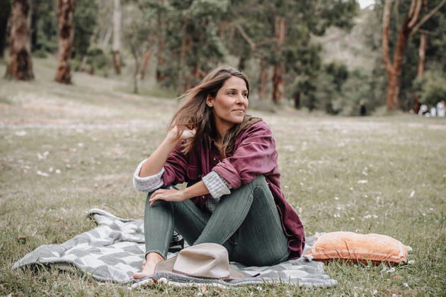 IMAGO Creative: Jahreszeit Fr?hling, Picknick Cheerful female sitting on plaid on meadow in woods and looking away while enjoying picnic in Australia Copyright: xAlexxBascuasx Model Released