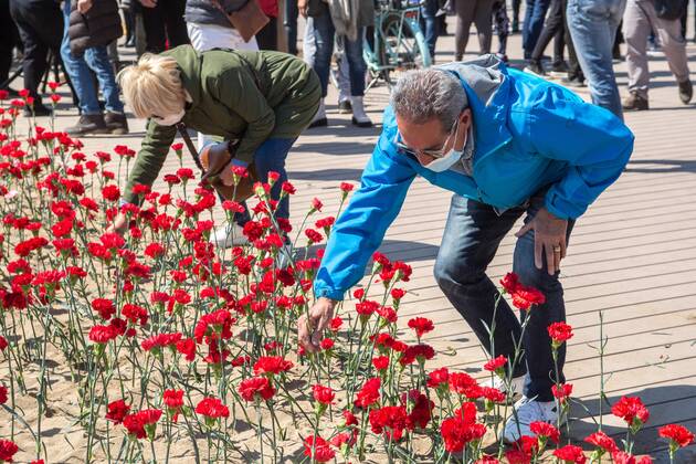 April 18, 2021, Barcelona, Catalonia, Spain: People are seen putting carnation seedling on beach sand.Stop Mare Mortum, a platform that aims to promote a change in European immigration and immigration policies in order to ensure that human rights are guaranteed and respected, has carried out, on Barceloneta beach in Barcelona, an visual action to denounce the constant deaths in the Mediterranean and the Atlantic. Some 150 people have carried out a carnation planting on behalf of the more than 1200 people who died during 2020 on the route to reach the Canary Islands. Barcelona Spain - ZUMAd159 20210418_zia_d159_015 Copyright: xThiagoxPrudenciox
