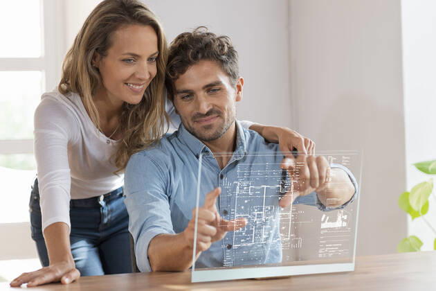 Mid adult couple looking at floor plan over transparent screen at home model released Symbolfoto property released SBOF03696