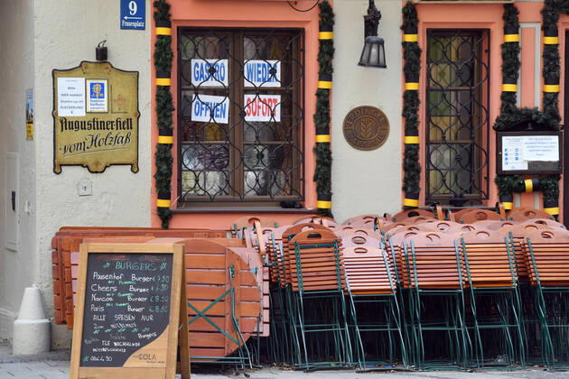 Themenbild: Coronavirus Pandemie Folgen fuer die Gastronomie: GASTRO WIEDER OEFFNEN SOFORT Im Fenster eines bayerischen Restaurants in Muenchen fordern die Eigentuemer die sofortige Oeffnung der Gastronomie. Uebereinander gestapelte Stuehle und Tische lehnen an der Hauswand.