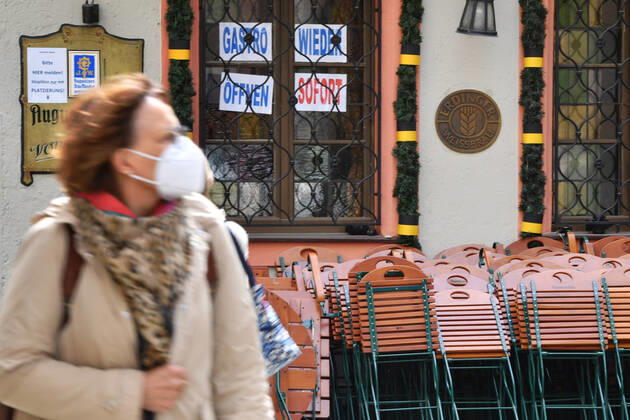 Themenbild: Coronavirus Pandemie Folgen fuer die Gastronomie: GASTRO WIEDER OEFFNEN SOFORT Im Fenster eines bayerischen Restaurants in Muenchen fordern die Eigentuemer die sofortige Oeffnung der Gastronomie. Uebereinander gestapelte Stuehle und Tische lehnen an der Hauswand. Passanten gehen mit Mundschutz,Maske vorbei.