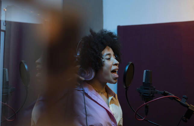 IMAGO Creative: 2021 Favoriten IMAGO Creative: Kreative Renaissance -- der junge Entrepreneur Black female singer performing song against microphone with pop filter while standing and looking forward in sound studio Copyright: xJosexCarlosxCerdenox Model Released