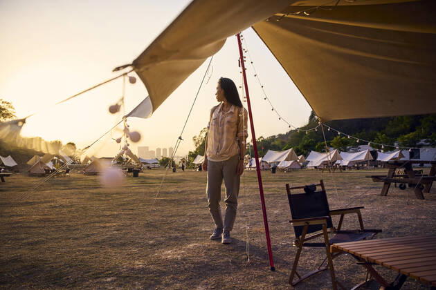 IMAGO Creative: Ende des Sommers Ethnic Asian woman with sunglasses having a relaxing time standing looking away in camping area during sunset time Copyright: xLuisxGomezx Model Released