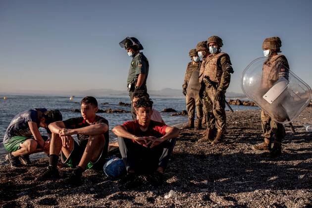 Morocco immigrants rest after reaching El Tarajal beach in the Spanish city of Ceuta, located in northern Africa, as members of the Spanish Army (R) and a member of the Guardia Civil (L) look on, 19 May 2021. Spain s Government considers that the massive arrival of some 8,000 irregular migrants to Ceuta from Morocco since 18 May is an assault on the border caused by the lack of control of the border by Morocco s Governmet and not a migratory crisis. Situation at El Tarajal beach in the Spanish city of Ceuta !ACHTUNG: NUR REDAKTIONELLE NUTZUNG!  Copyright: xBraisxLorenzox GRAF1057 20210519-637570249347369674