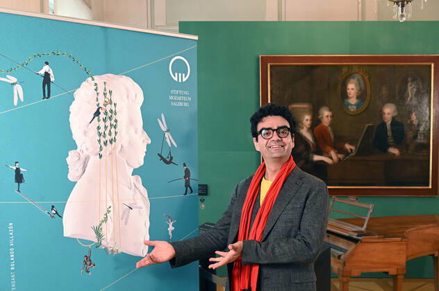 Pressekonferenz zur Programmpräsentation der Mozartwooche 2022 in Salzburg, am 19.05.21. Das Bild zeigt den Intendaten der Mozartwochen, Rolando Villazon während seines Vortrags zur Programmpräsentation. Im Hintergrund ist ein Bild der Familie Mozart zu sehen. Im Vordergrund deutet Herr Villazon auf einRollUp der Mozartwochen 2021 - Pressekonferenz zur Programmpräsentation der Mozartwooche 2022 in Salzburg, am 19.05.21