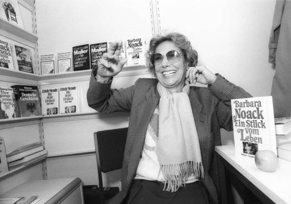 Barbara Noack (Autorin) 10 84 hör Barbara Noack im Oktober 1984 während der Frankfurter Buchmesse Messe Literaturmesse Literatur Frankfurt Main Deutschland deutsch deutsche Frau Schriftstellerin Literatur german female writer author quer halb sitzend Messestand lachend gestikulierend sw