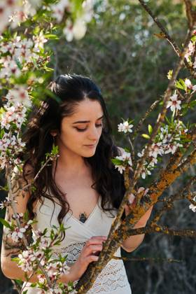 Young female with tattooed arm wearing white dress and standing in flowers of tree looking down, Model released, Property released Copyright: xCristianxBlazquezx MR