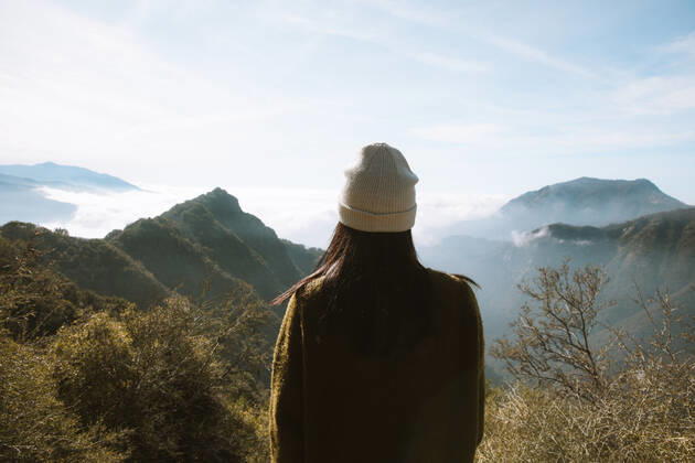 Back view of unrecognizable woman in warm clothes standing alone on viewpoint and looking at foggy mountain ridges covered fluffy clouds in Sequoia National Park under blue sky in USA, Model released Copyright: xLeirexUnzuetax MR