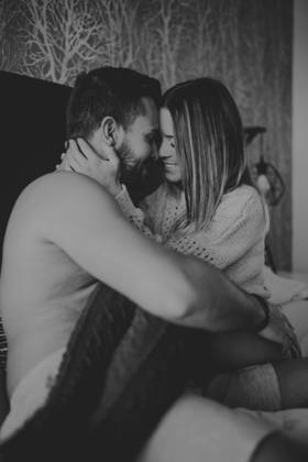 Cheerful young man and woman smiling and cuddling while lying on comfortable bed at home together, Model released Copyright: xMiguelxVallsx MR
