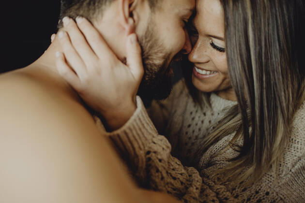 Cheerful young man and woman smiling and cuddling while lying on comfortable bed at home together, Model released Copyright: xMiguelxVallsx MR
