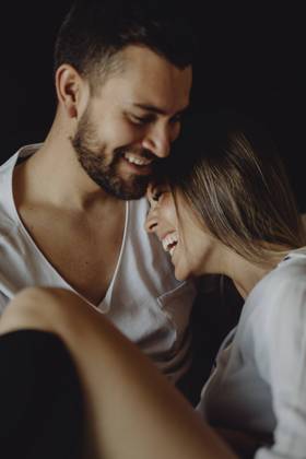 Cheerful young man and woman smiling and cuddling while sitting on comfortable bed at home together, Model released Copyright: xMiguelxVallsx MR