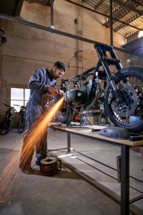 Bearded worker in overall using angle grinder while polishing metal details of custom motorcycle in workshop Copyright: xPhilippexDegrootex Model Released