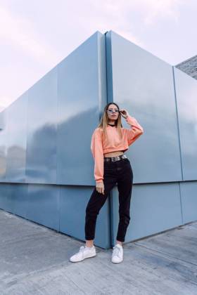 Confident female wearing jeans with top and orange shirt with stylish sunglasses standing near wall, Model released Copyright: xJosexDexJesusxSaldanax MR