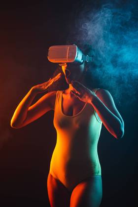 Anonymous astonished ethnic female with open mouth exploring virtual reality in headset on black background, Model released Copyright: xLeonardoxBorgesx MR