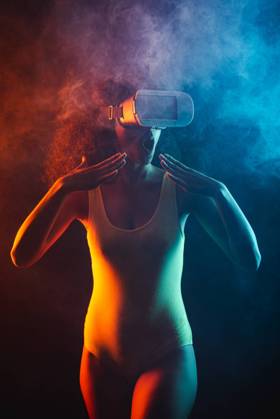 Anonymous astonished ethnic female with open mouth exploring virtual reality in headset on black background, Model released Copyright: xLeonardoxBorgesx MR