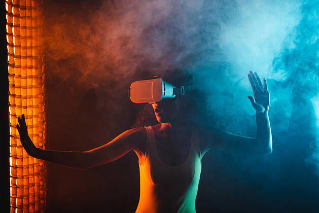 Anonymous astonished ethnic female with open mouth exploring virtual reality in headset on black background, Model released Copyright: xLeonardoxBorgesx MR
