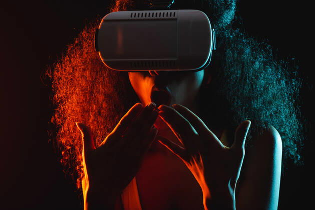 Anonymous astonished ethnic female with open mouth exploring virtual reality in headset on black background, Model released Copyright: xLeonardoxBorgesx MR