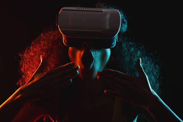 Anonymous astonished ethnic female with open mouth exploring virtual reality in headset on black background, Model released Copyright: xLeonardoxBorgesx MR