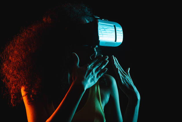 Anonymous astonished ethnic female with open mouth exploring virtual reality in headset on black background, Model released Copyright: xLeonardoxBorgesx MR