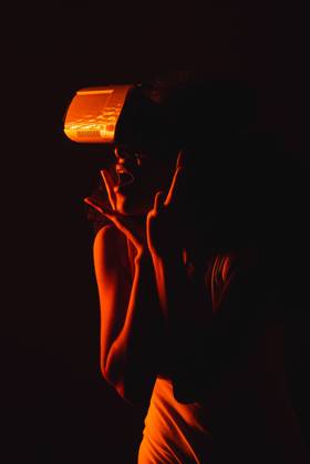Anonymous astonished ethnic female with open mouth exploring virtual reality in headset on black background, Model released Copyright: xLeonardoxBorgesx MR