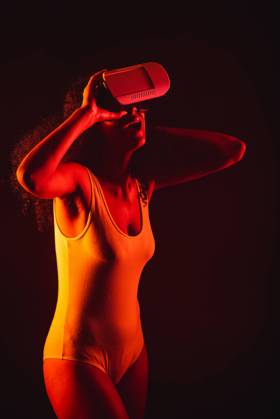 Anonymous astonished ethnic female with open mouth exploring virtual reality in headset on black background, Model released Copyright: xLeonardoxBorgesx MR