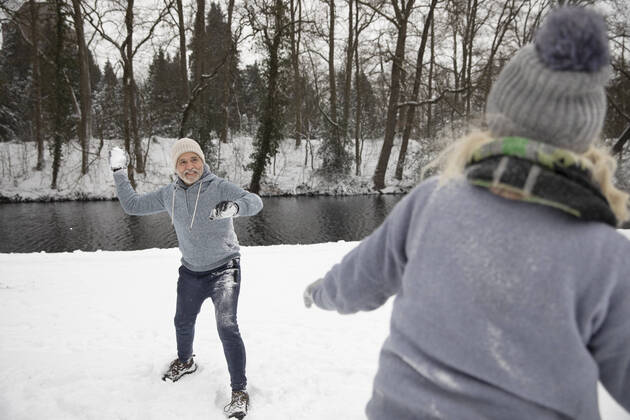 IMAGO Creative: Alternativer Wintersport Man throwing snowball on woman during winter model released Symbolfoto FVDF00104
