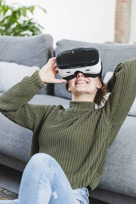 Smiling woman in sweater holding Virtual reality headset at home model released Symbolfoto property released MCVF00801