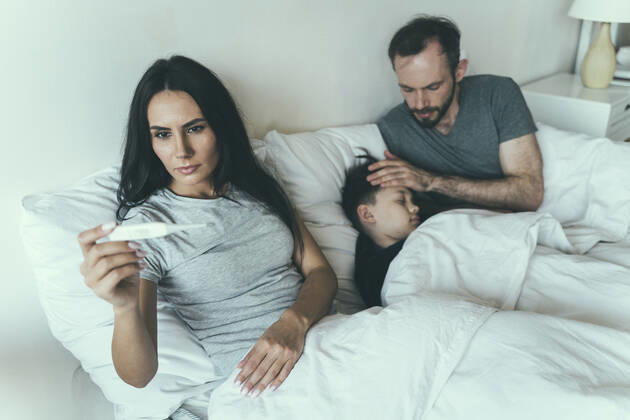 Woman measuring temperature while father taking care of son at home model released Symbolfoto property released OIPF00606