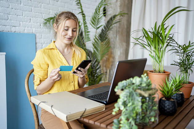 Female professional doing online payment through credit card while sitting at home office model released Symbolfoto property released RCPF01030