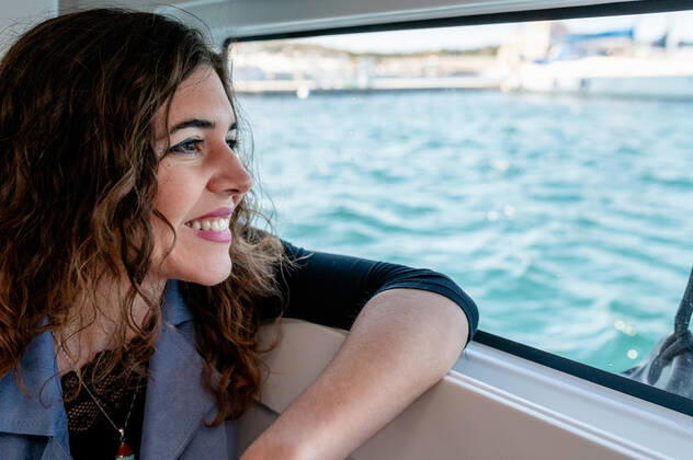 Tranquil female sitting in cabin of catamaran and looking out of window while admiring amazing view of sea on sunny day, Model released, Property released Copyright: xCarlosxPintaux MR