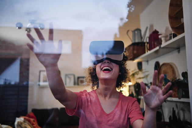 Cheerful young woman wearing virtual reality simulator seen through glass at home model released Symbolfoto property released ASGF00309