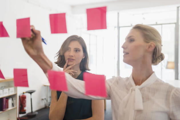 IMAGO Creative, Internationaler Frauenmonat, Entrepreneurinnen IMAGO Creative: Kreative Renaissance -- der junge Entrepreneur Young female entrepreneur looking at coworker writing on adhesive notes while discussing in office model released Symbolfoto property released DIGF15401