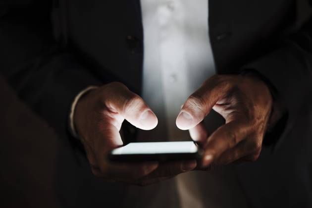 Male entrepreneur using smart phone in dark model released Symbolfoto EBBF04014