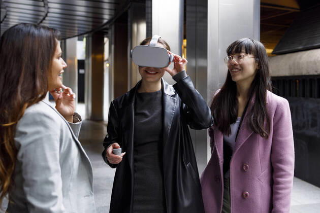 Smiling colleagues looking at businesswoman using virtual reality headset on walkway model released Symbolfoto IFRF00866