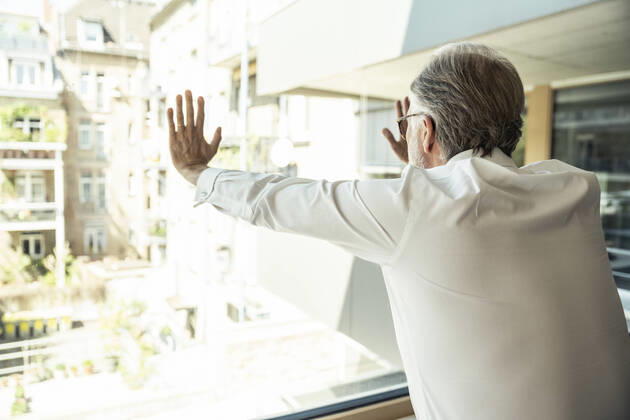 Male professional touching glass window while leaning at office model released Symbolfoto property released UUF23486