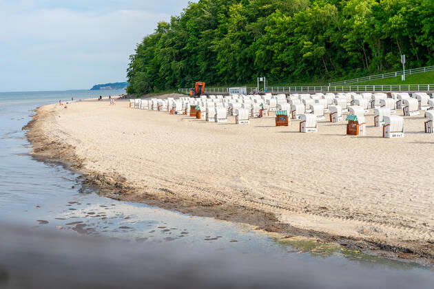 Ruegen, Sellin, Mecklenburg-Vorpommern, Germany - 10 june 2021: Holidaymakers go swimming on the beach of Sellin, several beach chairs to rest in the vacation area