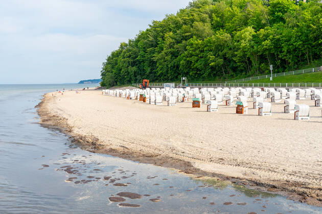 Ruegen, Sellin, Mecklenburg-Vorpommern, Germany - 10 june 2021: Holidaymakers go swimming on the beach of Sellin, several beach chairs to rest in the vacation area