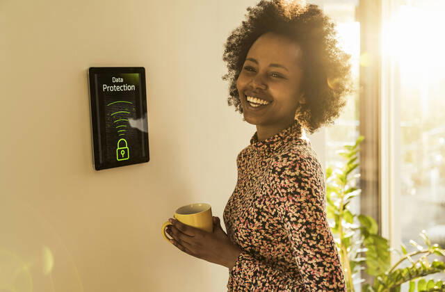 Cheerful woman with coffee cup standing by home automation device model released Symbolfoto property released UUF23544