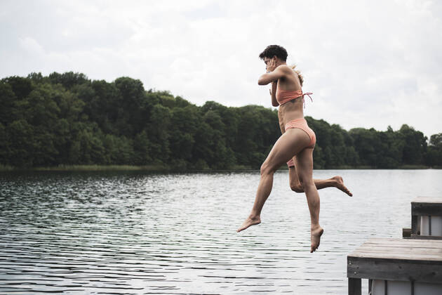 IMAGO Creative: Jahreszeit Sommer, Festivals Friends jumping in lake in Poland in orange swimsuit in summer Garbicz, Lubusz Voivodeship, Poland CR_PIDODS210721-787655-01 ,model released, Symbolfoto