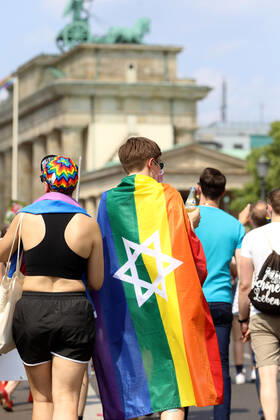 Berliner CHRISTOPHER STREET DAY 2021 - CSD - Am 24. Juli 2021 zieht der CSD in Berlin unter dem Motto SAVE OUR COMMUNITY SAVE YOUR PRIDE zum 43. Mal durch die Hauptstadt. Demoteilnehmer vor dem Brandenburger Tor trägt Regenbogenflagge mit Davidstern. Die bunte CSD-Parade startete in diesem Jahr als Demonstration an der Leipziger Straße, führte über den Potsdamer Platz, vorbei am Denkmal für die im Nationalsozialismus verfolgten Homosexuellen zum Brandenburger Tor und über die Siegessäule zur Urania. Aufgrund der Corona-Pandemie fand die Demonstration ausschließlich unter Einhaltung der vom Berliner Senat erlassenen Vorgaben statt. Die in den Vorjahren übliche Abschlusskundgebung musste daher ausfallen.